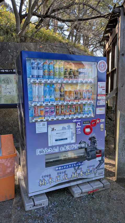 鳥居前の自転車置き場まで戻ってきた。自販機があり、「中世のサムライヒーロー 楠木正成・楠木正行」と書かれている 20260301-nankou-jihanki.jpg